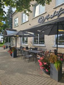 an outdoor patio with tables and chairs and umbrellas at Muskatas in Rietavas