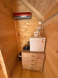 a small kitchen in a wooden cabin with a refrigerator at ORAHOVSTICA TRAIL - Glamping in Dupilo