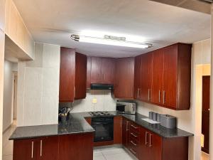 a kitchen with wooden cabinets and a black counter top at Thetsane Ridge in Maseru