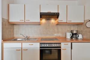 a kitchen with white cabinets and a sink at FeWo Grytz in Dahme +10 photos