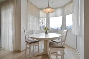 a white dining room with a white table and chairs at FeWo Grytz in Dahme