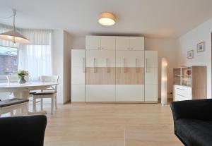 a living room with a table and a kitchen with white cabinets at FeWo Grytz in Dahme