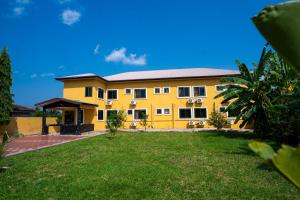 a yellow house with a lawn in front of it at Eastern Plus Hotel in Somanya
