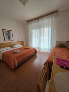 a bedroom with two beds and a table and a window at The green house in Malcesine