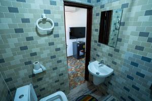 a bathroom with a sink and a toilet and a mirror at Eastern Plus Hotel in Somanya