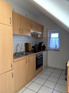 a kitchen with wooden cabinets and a sink and a window at Seewiefken 2 Dümmerblick in Lembruch