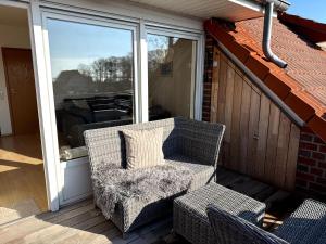a wicker chair sitting on a porch with a window at Seewiefken 2 Dümmerblick in Lembruch