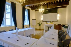 a room with white tables and chairs and a projection screen at Maison Philippe Le Bon Hôtel, Restaurant & Bar le 19 in Dijon