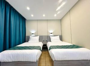 zwei Betten in einem Zimmer mit blauen Vorhängen in der Unterkunft Ashid in Ulaanbaatar