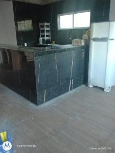 a kitchen with a black counter and a refrigerator at Lajedalu in Aquiraz