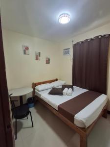 a bedroom with a bed and a chair and a table at D' TRAVELLERS Inn PUERTO in Puerto Princesa City