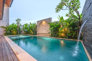 ein Swimmingpool mit Wasserfall in einer Villa in der Unterkunft Villa Asvari in Tabanan