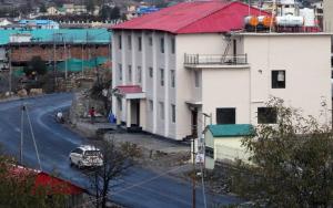 a building with a red roof and a car on a street at VijayLord's palace Badrinath in Badrinath