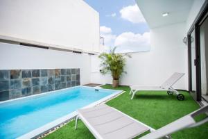 a swimming pool in a house with a patio and grass at Stylish Central Three Bed Duplex with Private Pool in Flic-en-Flac