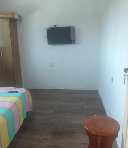 a room with a bed and a tv on a wall at Lajedalu in Aquiraz
