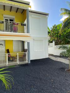 a white house with a balcony and a fence at Mon petit coin de paradis in Morne-à-lʼEau