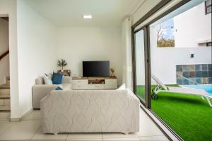 a living room with a couch and a tv at Stylish Central Three Bed Duplex with Private Pool in Flic-en-Flac