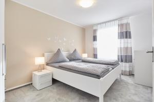 a white bedroom with a bed and a window at Ferienhaus Lina in Borkum