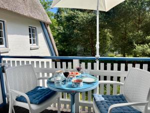 a table and chairs on a patio with an umbrella at Achtern Diek 12b - Wohnung 5 in Müggenburg