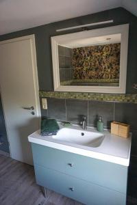 a bathroom with a sink and a mirror at Wohnung Burghaus 5 OG in Krummhörn +12 photos