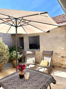 ein Tisch mit Sonnenschirm und zwei Stühlen in der Unterkunft Casa 5A - Refúgio Intimo e privado com design e pátio acolhedor in Oliveira do Mondego