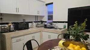 a kitchen with white cabinets and a table with a bowl of oranges at Windfall Wine Farm in Robertson