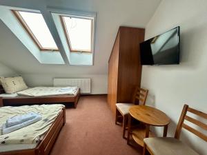 a room with two beds and a table and a tv at Noclegi Kołek in Pogórze