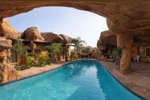 a pool in a house with a rock wall at Ndou The Rocks Lodge in Hammanskraal Station