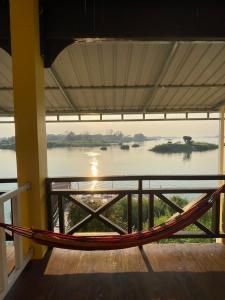 a hammock in a room with a view of a river at Tena Don Det Sunset Guest House in Don Det