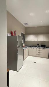 a kitchen with a stainless steel refrigerator and white cabinets at ZA apartment in Al Ahsa