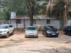 three cars parked in a parking lot in front of a house at Eshwaraa Cottage in Palni +1 photo