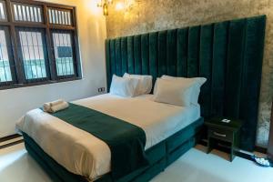 a bedroom with a large bed with a green headboard at Villa Bee in Wennappuwa