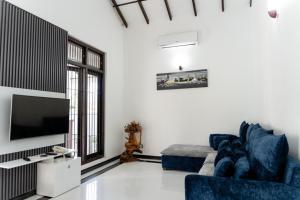 a living room with a blue couch and a tv at Villa Bee in Wennappuwa