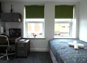 a bedroom with a bed and a desk and two windows at Victoria House - Deluxe Studios in Coventry City Centre, free parking, by COVSTAYS in Coventry