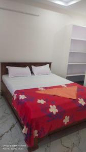 a bed with a red blanket with flowers on it at Rr suites in Kākināda
