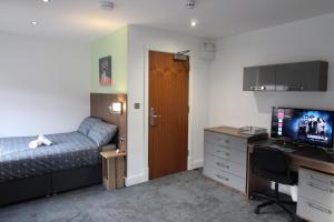 a bedroom with a bed and a desk with a television at Victoria House - Deluxe Studios in Coventry City Centre, free parking, by COVSTAYS in Coventry