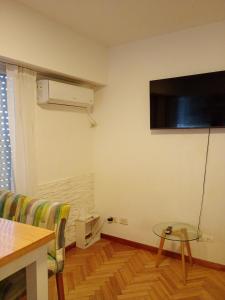 a living room with a table and a tv on the wall at Aire Porteño in La Porteña