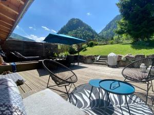 a patio with chairs and a table and an umbrella at L annexe in Saint-Jean-d'Aulps