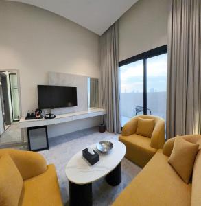 a living room with two chairs and a television at Triple A Hotel in Riyadh