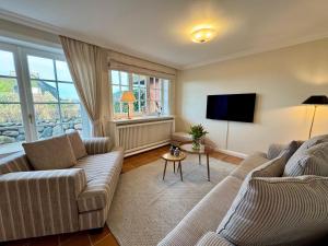 a living room with two couches and a flat screen tv at Landhaus-Duenenhof in Rantum
