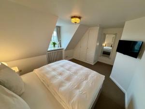 a bedroom with a white bed and a window at Landhaus-Duenenhof in Rantum