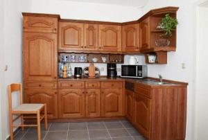 a kitchen with wooden cabinets and a microwave at Ferienwohnung-Hoffmann-Harzgerode in Harzgerode