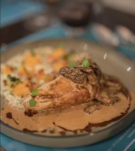 a plate of food with a piece of chicken with sauce at L'aube de Vouglans 5 kms des plages in Pont-de-Poitte +17 photos