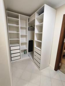 a walk in closet with white shelves and a tv at Santa Marina Breeze - One bedroom apartment in Sozopol