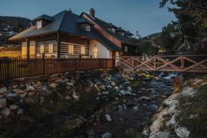 a wooden house with a bridge over a river at Chaloupka Kunčice in Staré Město