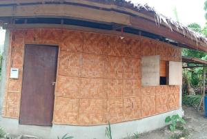 a small brick building with a brown door at Kalma Kubo Siargao in San Isidro +2 photos