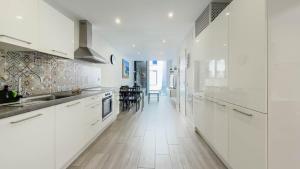 a kitchen with white cabinets and a long hallway at Guanarteme Vista Surf, Las Canteras in Las Palmas de Gran Canaria +13 photos
