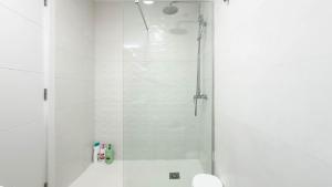 a white bathroom with a shower and a toilet at Guanarteme Vista Surf, Las Canteras in Las Palmas de Gran Canaria