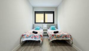 two beds in a room with a window at Guanarteme Vista Surf, Las Canteras in Las Palmas de Gran Canaria