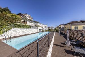 a swimming pool on a balcony with chairs and umbrellas at Maison Selva - Corte Brunati Villetta Deluxe con piscina e garage in Salò